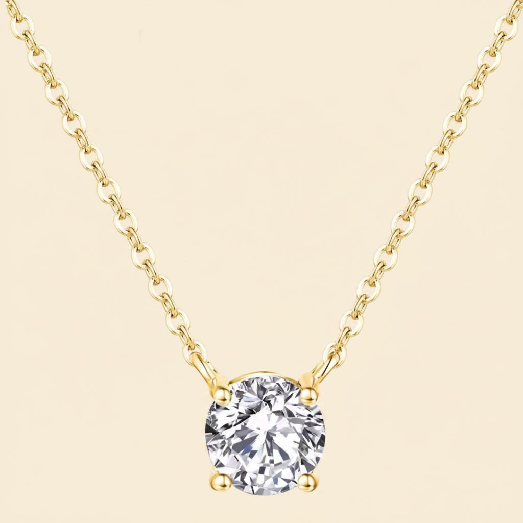 Gold necklace with a clear gemstone pendant on a white background